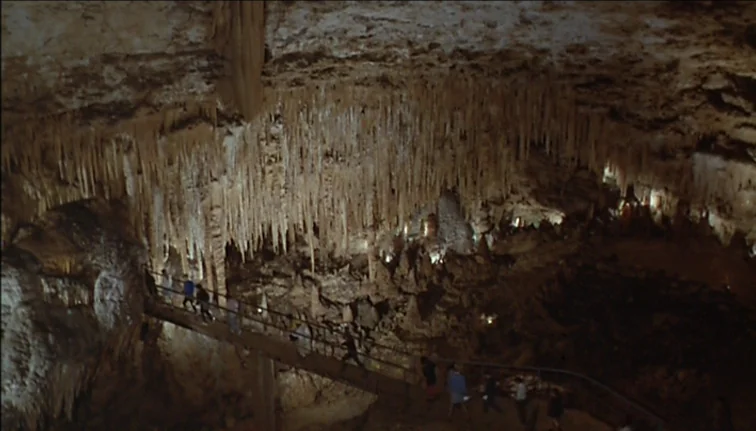 Le Boucher (1970) movie still: establishing — A vast underground limestone cavern features massive ceiling stalactites and rocky terrain. A group of…