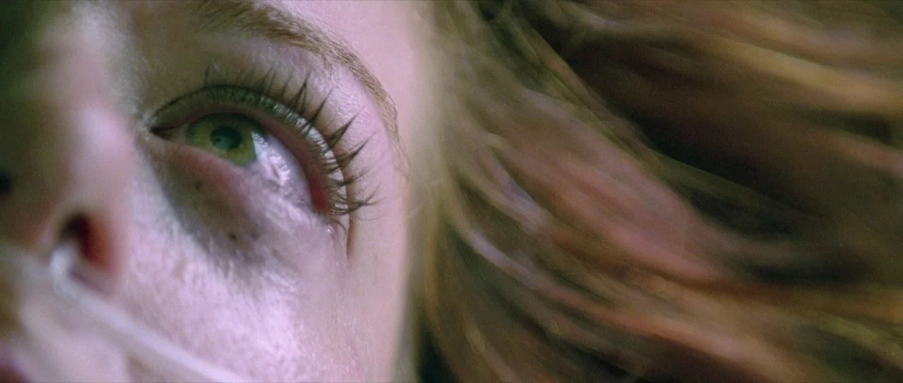 The Mothman Prophecies (2002) movie still: closeup — A close-up view shows a person lying down with a nasal cannula tube. The person's eye is open…