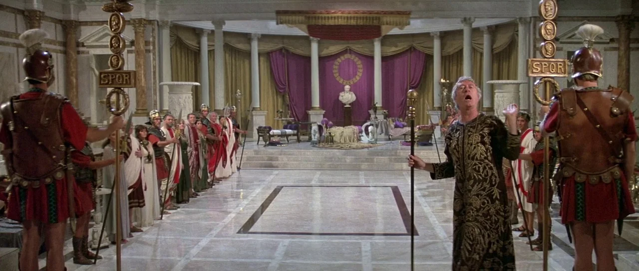 History of the World: Part 1 (1981) movie still: wide — A spacious Roman hall features polished marble floors and purple drapes behind a throne.…