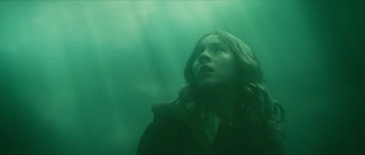 The Lovely Bones (2009) movie still: medium — A teenage girl is submerged underwater in a murky, green-tinted body of water. She looks upward toward…