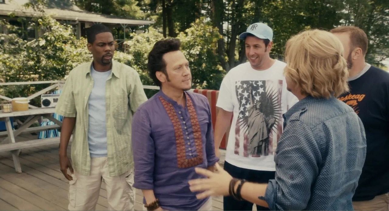 Grown Ups (2010) movie still: medium — A wooden deck at a lakeside property features five men standing in a group. The men wear casual clothing and…