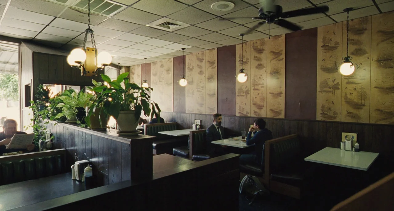 The Killing of a Sacred Deer (2017) movie still: wide — A diner interior features dark wood-paneled walls and wallpaper with repeating woodland…