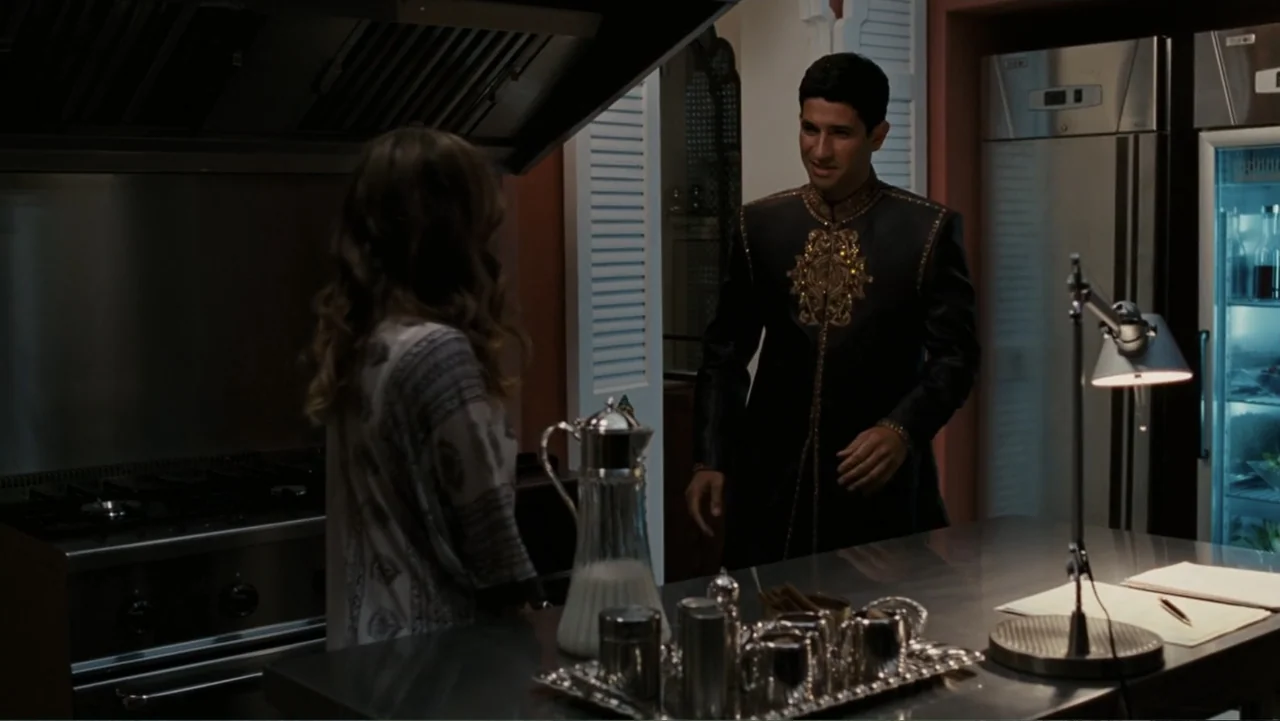Sex and the City 2 (2010) movie still: medium — A modern kitchen features a stainless steel island and a large industrial refrigerator. A man in a…