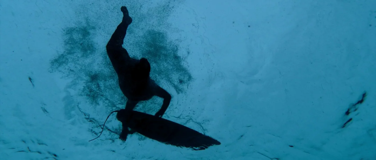 The Shallows (2016) movie still: medium — An underwater view looking toward the surface of the sea. A lone surfer descends through the water while…