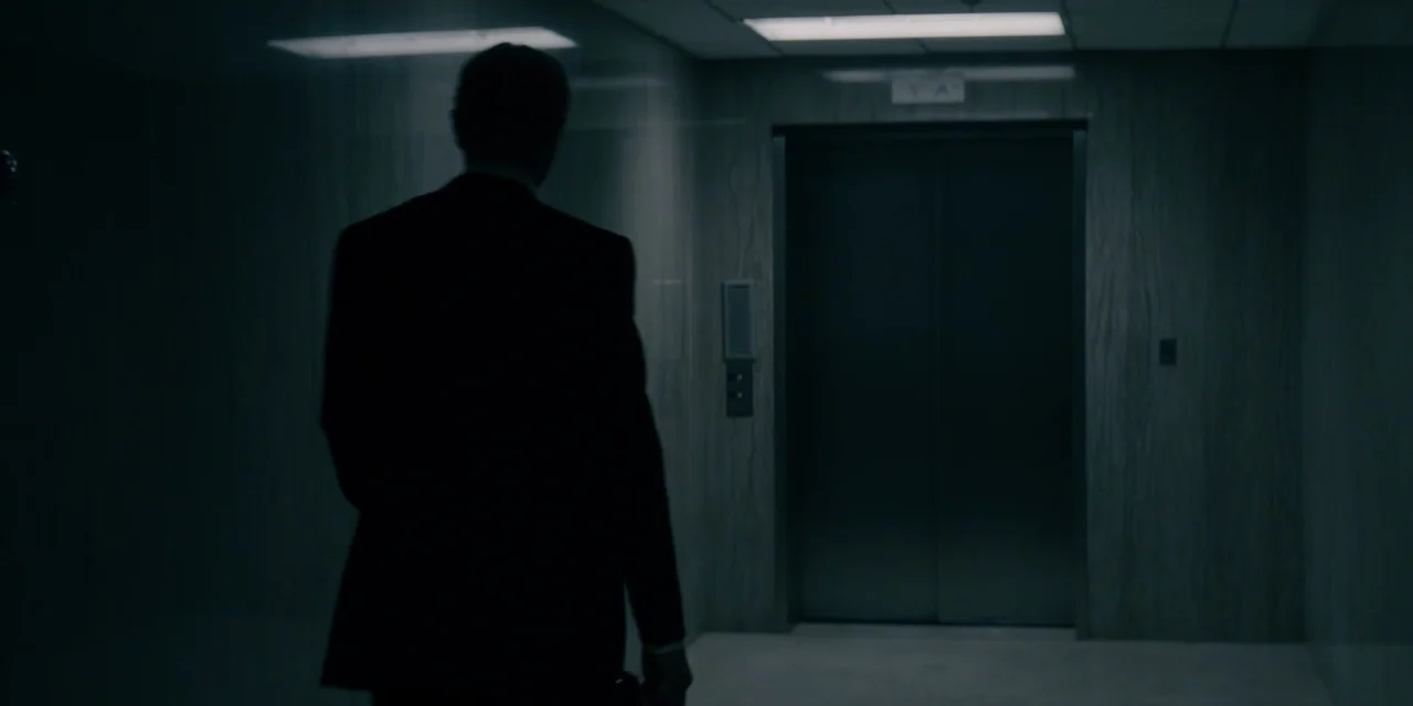 Mark Felt: The Man Who Brought Down the White House (2017) movie still: medium — A dimly lit office elevator lobby features wood-paneled walls and a…