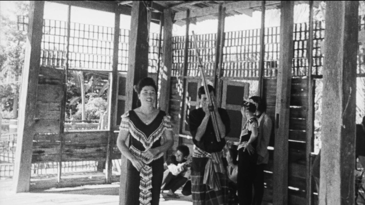 Mysterious Object at Noon (2000) movie still: fullbody — An open wooden pavilion built on stilts features lattice walls and rustic timber framing.…