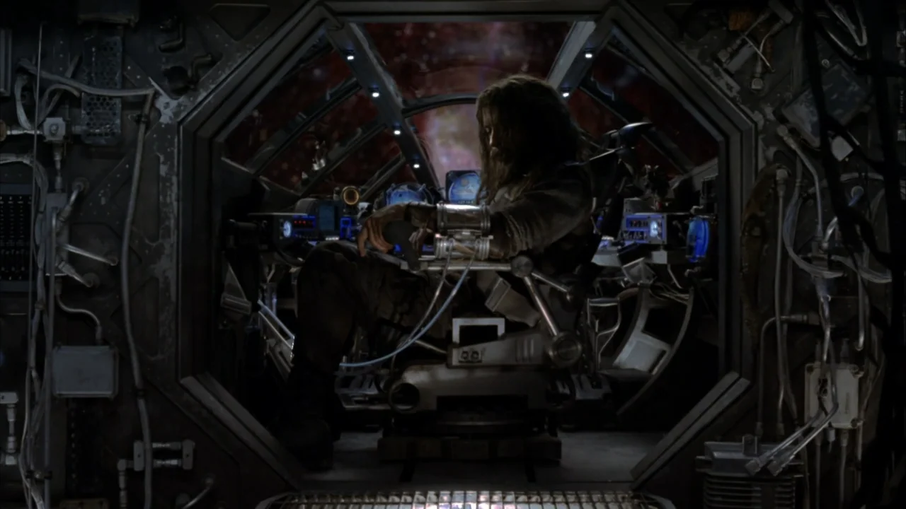The Chronicles of Riddick (2004) movie still: medium — A high-tech spacecraft cockpit features metallic panels and glowing blue interface displays.…