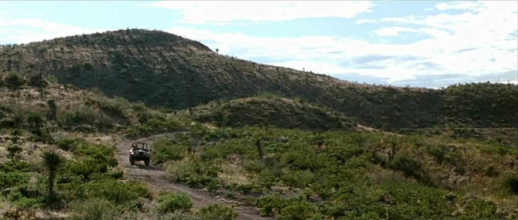 The Three Burials of Melquiades Estrada (2005) movie still: wide — A vast, arid landscape of rolling hills covered in sparse desert scrub and cacti.…