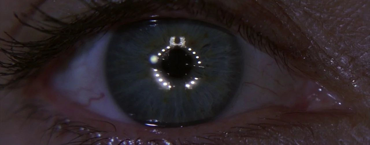 Event Horizon (1997) movie still: closeup — An extreme close-up focuses on a single human eye. Light from a ring source reflects clearly in the pupil.