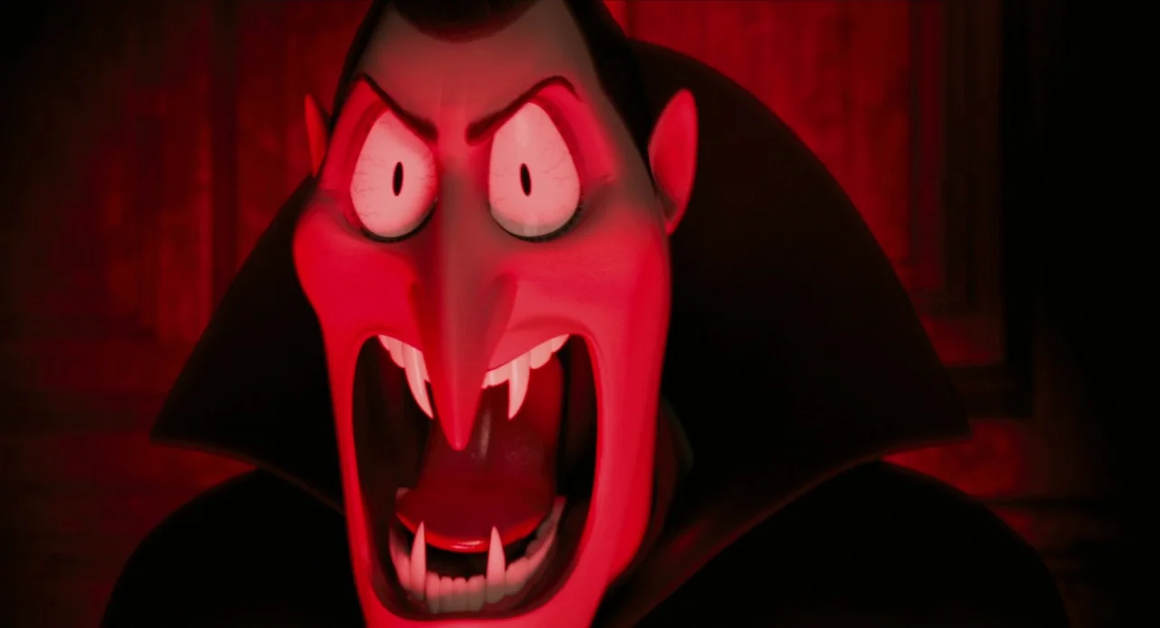 Hotel Transylvania movie still: closeup — A character with a sharp, elongated face occupies the frame against a red backdrop. He is shouting with…