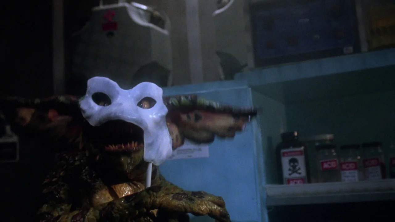 Gremlins 2: The New Batch movie still: closeup — A dark science laboratory contains glass chemical jars labeled with hazard symbols. A reptilian…