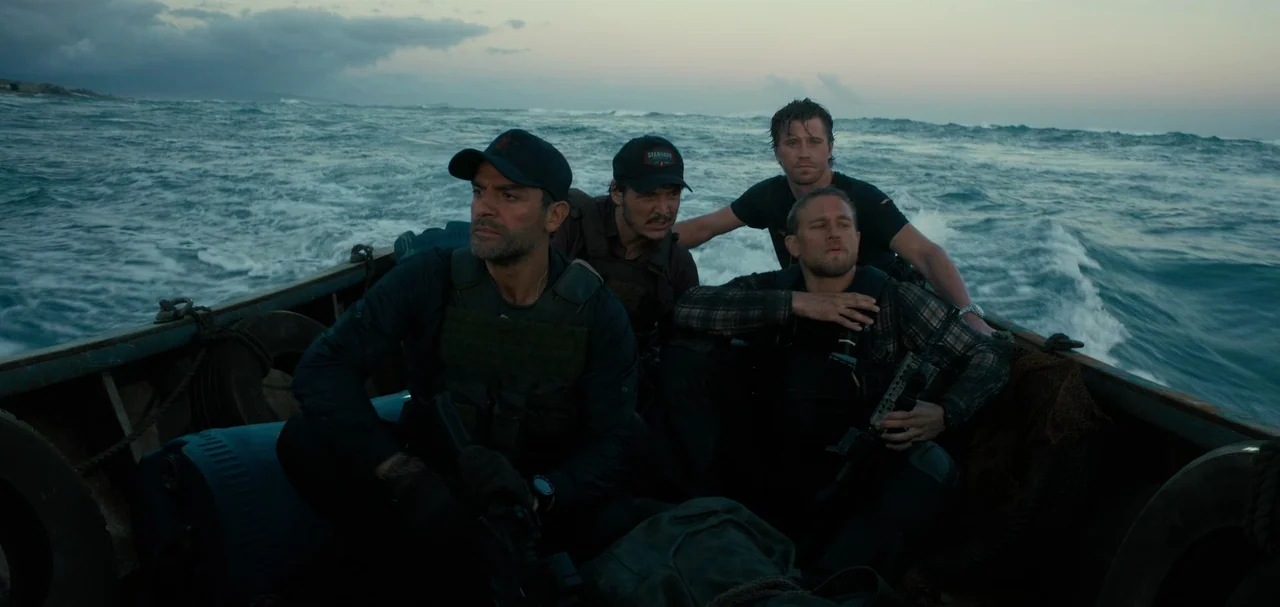 Triple Frontier (2019) movie still: medium — Four men in tactical gear ride in a small motorized boat across choppy water. The scene takes place…