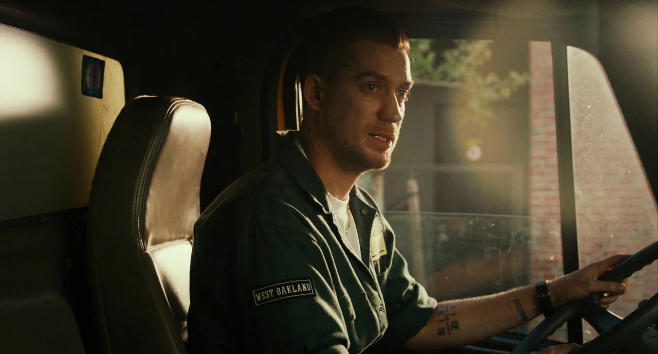 Blindspotting (2018) movie still: medium — A cramped truck cabin features dark plastic upholstery and a side window view. A young man sits in the…