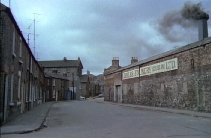 Quackser Fortune Has a Cousin in the Bronx (1970) movie still: establishing — A narrow industrial street in Dublin features rows of brick houses and…