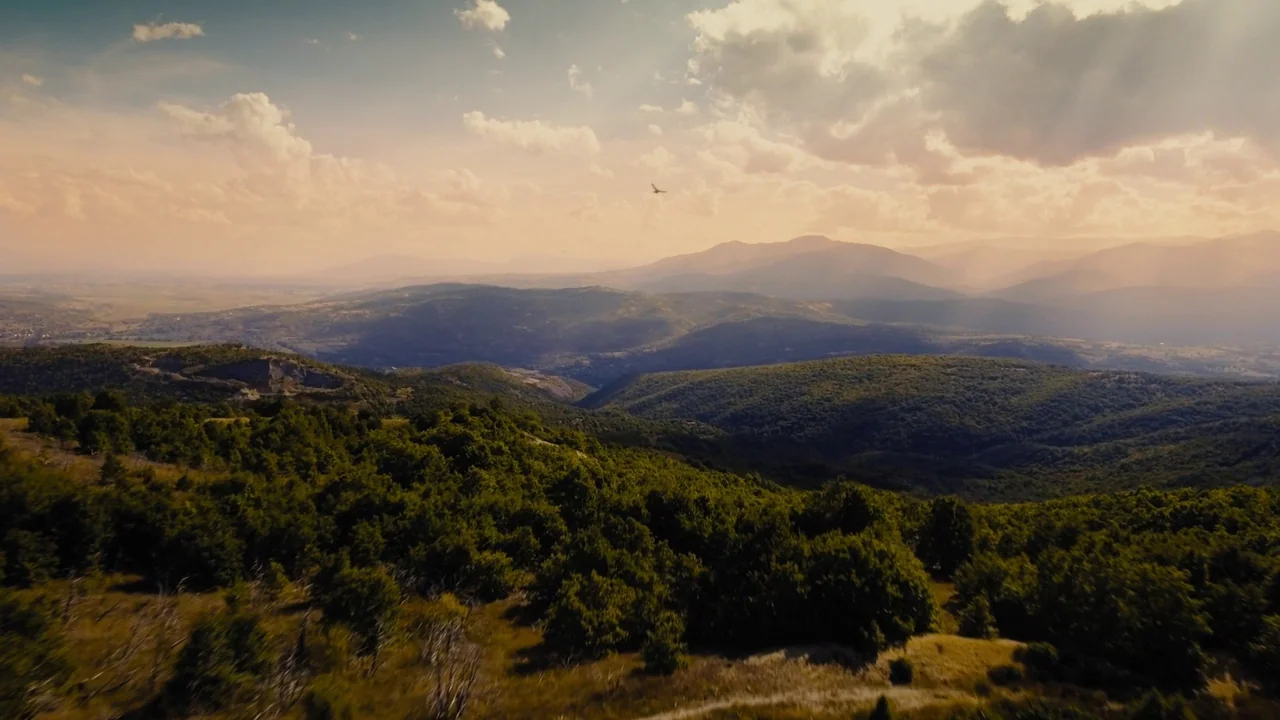 Fahrenheit 451 (2018) (2018) movie still: establishing — A vast mountain range stretches toward the horizon under a cloudy, golden-hued sky. A lone…