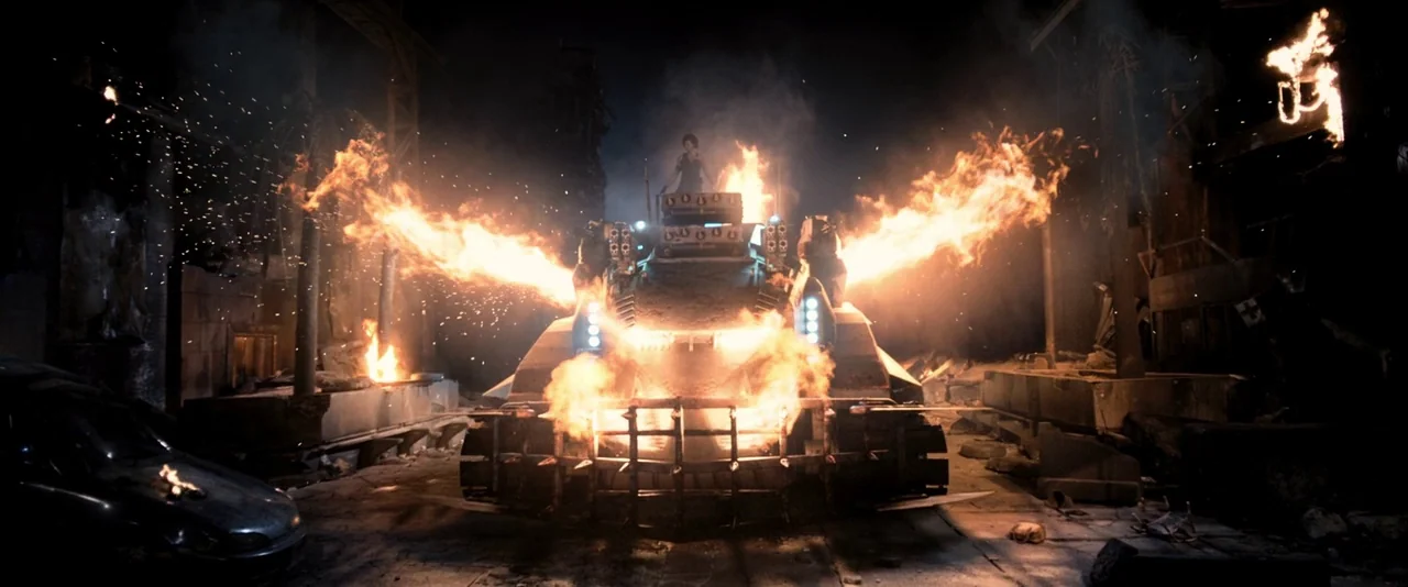Resident Evil: The Final Chapter (2016) movie still: wide — A destroyed city street at night features a burning, metal-plated military tank. A woman…