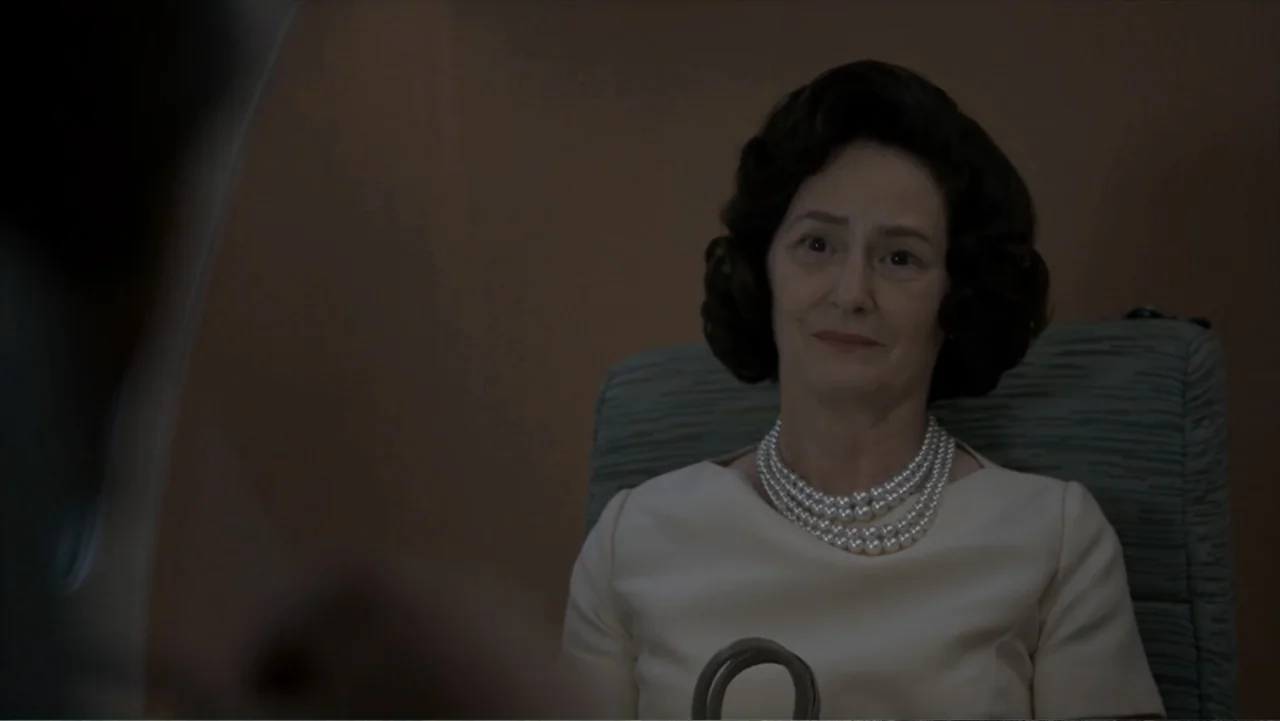 All the Way (2016) movie still: medium — An airplane cabin interior features a woman sitting in a textured grey chair. The woman wears a pearl…
