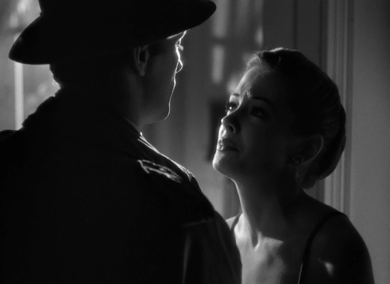 Out of the Past (1947) movie still: medium — A dimly lit room shows a silhouette of a man in a hat. A woman stands in the light looking up at him.