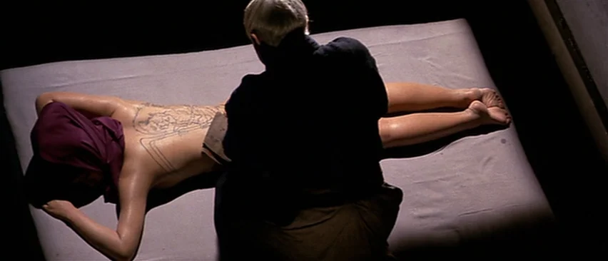Lone Wolf and Cub: Baby Cart in Peril (1972) movie still: medium — A dimly lit room with a person lying prone on a large fabric-covered mattress. An…