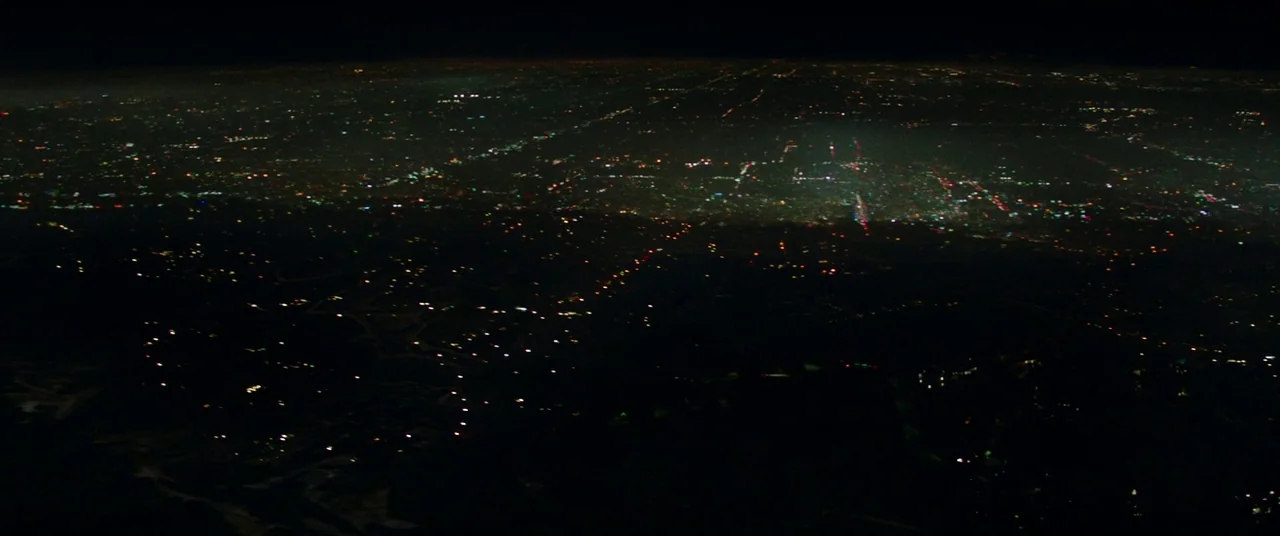 The Nice Guys (2016) movie still: establishing — A vast aerial view shows a sprawling metropolitan grid illuminated by scattered artificial lights.…