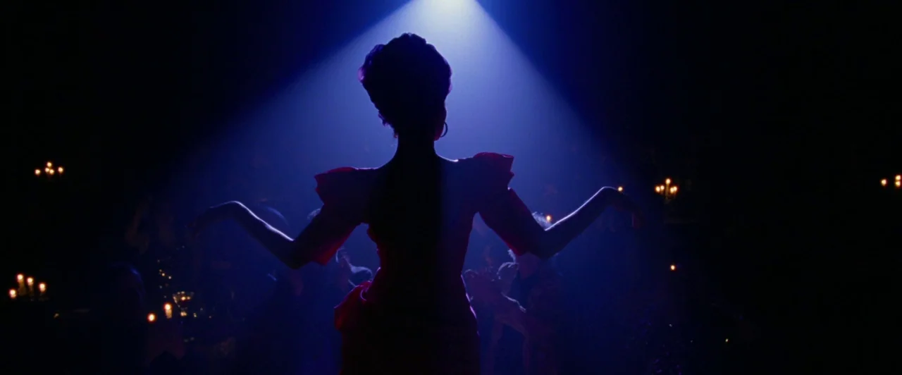 Lost River (2014) movie still: medium — A dark, dimly lit venue with small candle-lit tables surrounding a central dance floor. A woman in a dress…