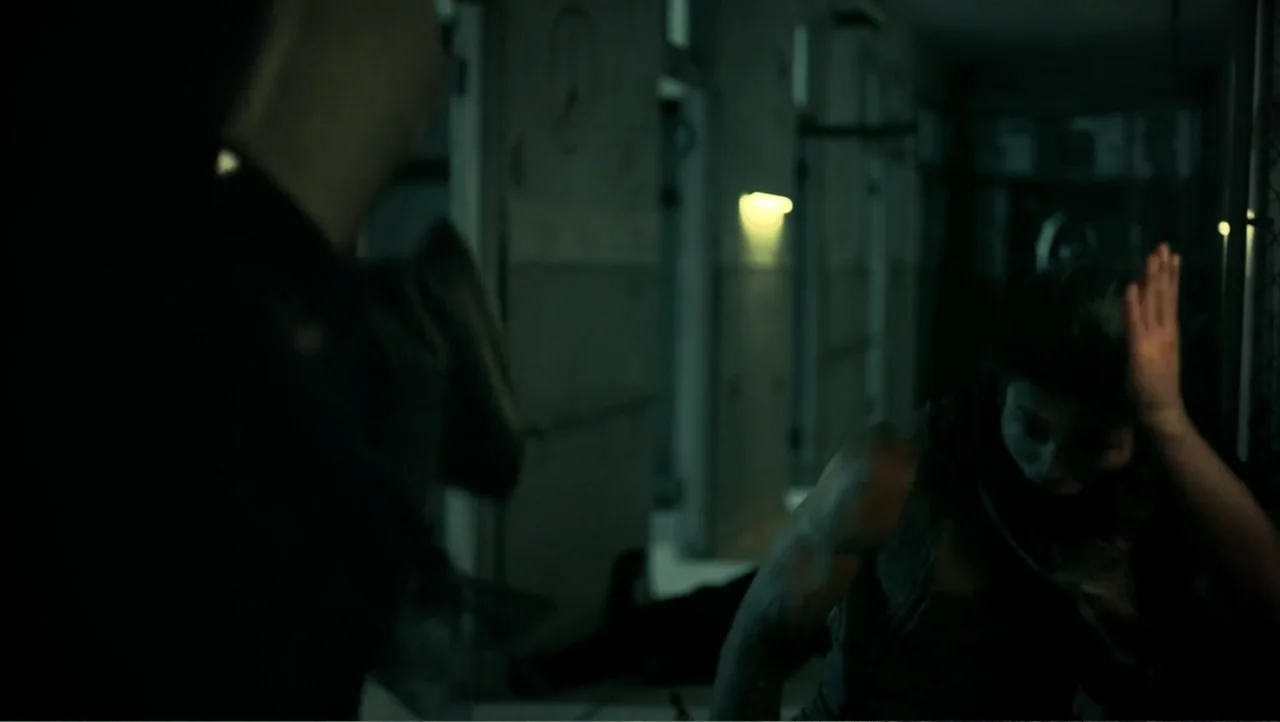 Shadow Master (2022) movie still: medium — An dimly lit, narrow corridor features clinical walls with closed doors and flickering light. A woman in…