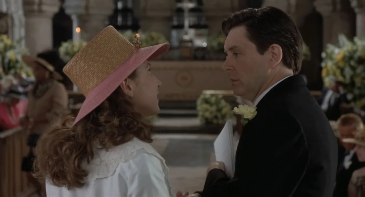 Four Weddings and a Funeral (1994) movie still: medium — A church interior with guests in the pews and floral arrangements at the altar. A woman…
