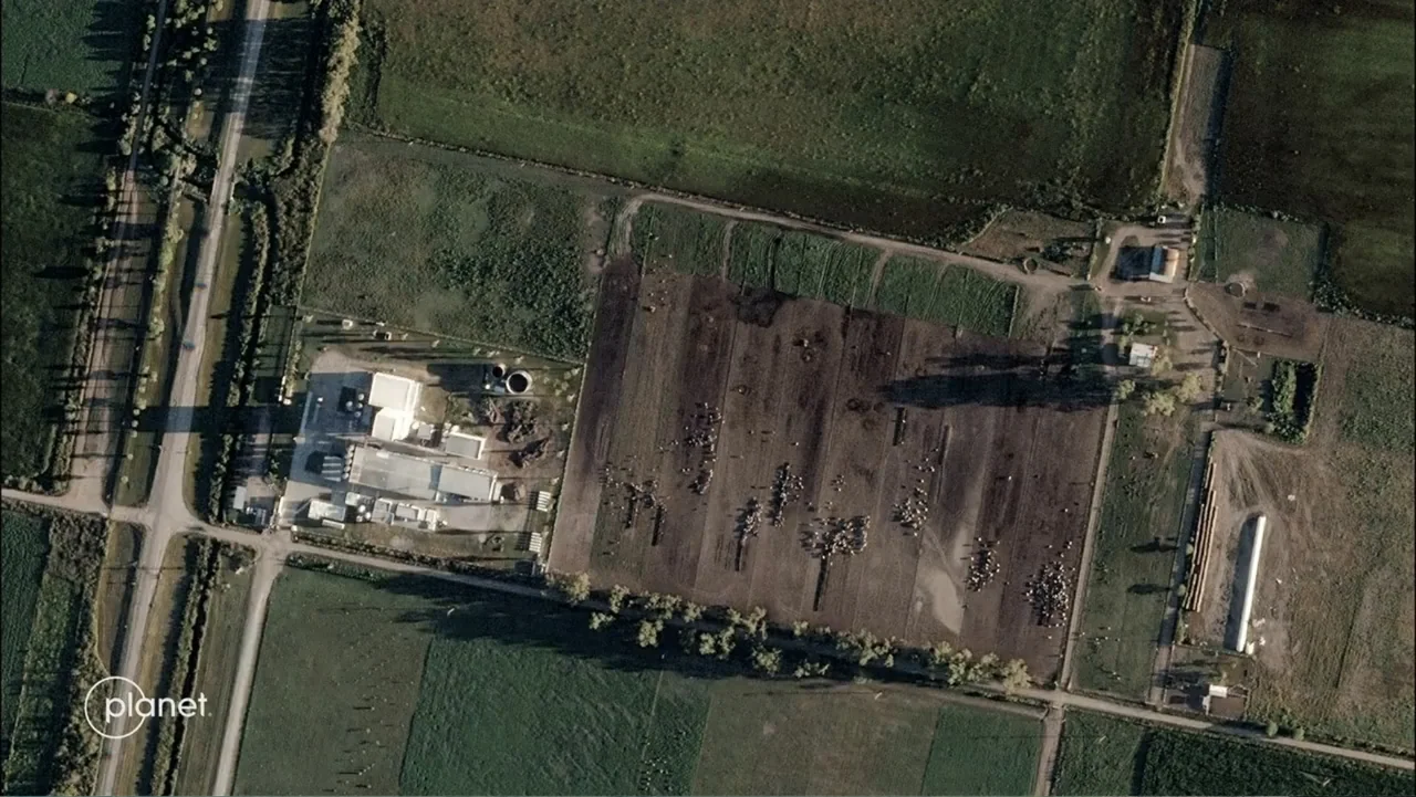 Wild Wild Space (2024) movie still: establishing — An aerial view of a rural livestock facility surrounded by agricultural fields and roads.…