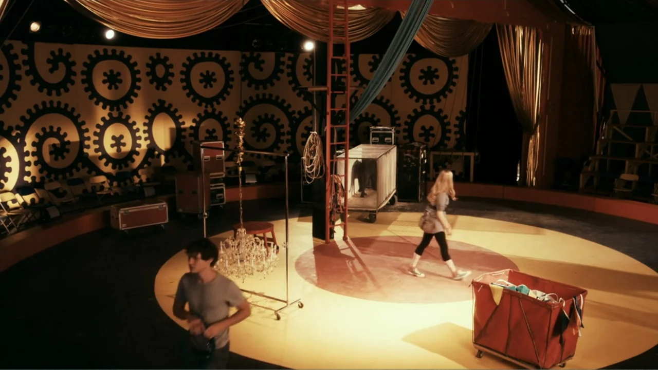 Sophie & Sheba (2010) movie still: wide — A circus ring with a spiral pattern wall and scattered equipment throughout. A man and a woman walk across…
