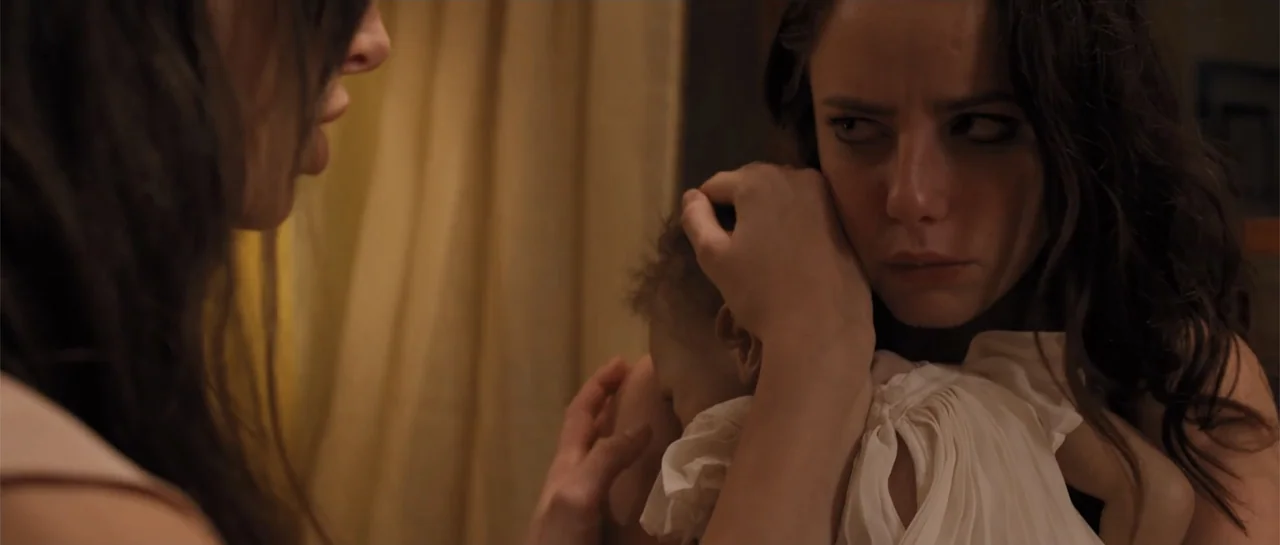 The Truth About Emanuel (2013) movie still: medium — A dimly lit room with draped curtains visible in the background. A woman cradles an infant…