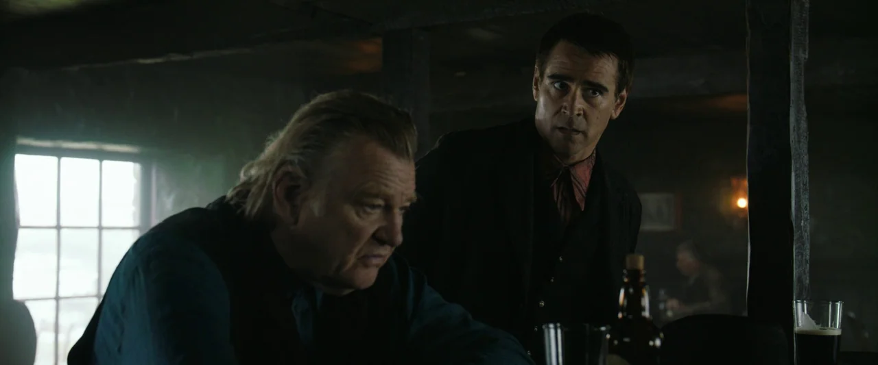 The Banshees of Inisherin (2022) movie still: medium — A dimly lit, rustic pub with dark wooden paneling and a hazy atmosphere. Two men sit at a…