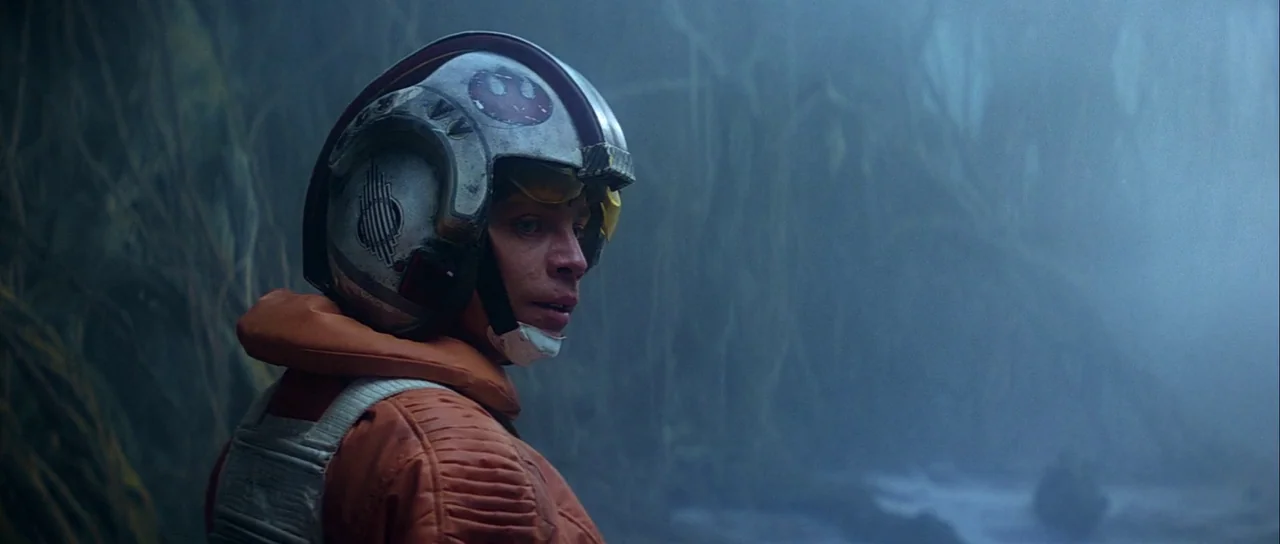 The Empire Strikes Back (1980) movie still: medium — A dense, foggy swamp filled with twisted tree roots and thick vegetation. A young male pilot in…