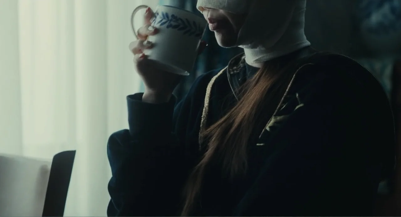 Winter in Sokcho (2025) movie still: medium — An interior space is illuminated by daylight filtering through a sheer white curtain. A person with…
