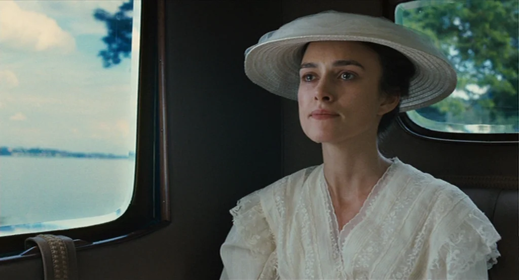 A Dangerous Method movie still: medium — The interior of a vintage train carriage features dark leather upholstery and a window. A woman wearing a…