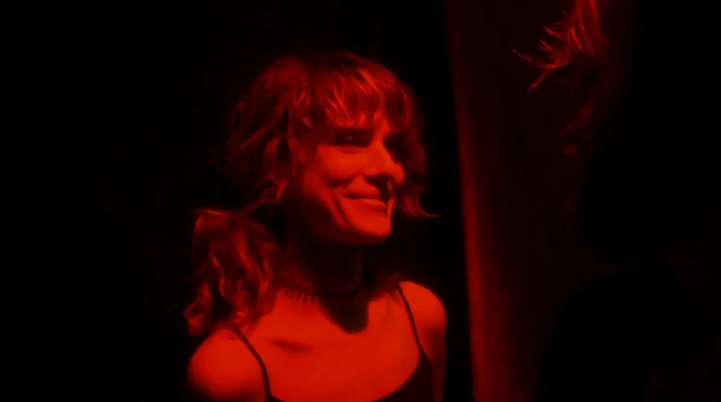 Humpday (2009) movie still: medium — A dark space lit only by deep red light. A young woman smiles toward someone outside the frame.