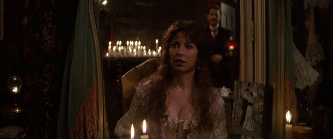 Tombstone (1993) movie still: medium — A dimly lit room is filled with numerous candles and antique Victorian furnishings. A woman sits at a vanity…