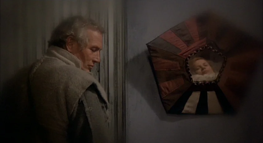 Quintet (1979) movie still: medium — A dark bedroom interior features a wall with a unique pentagonal fabric-wrapped mirror. An older man stands…