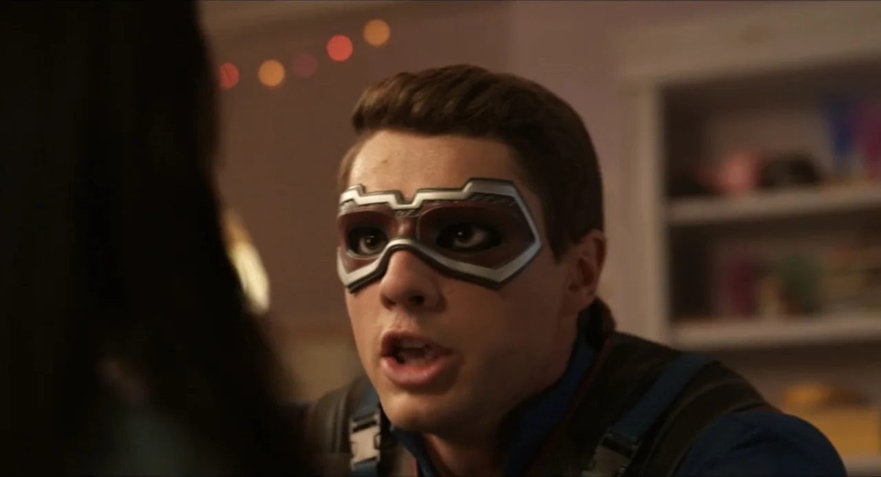 Henry Danger: The Movie (2025) movie still: closeup — A dimly lit room with out-of-focus shelves and warm string lights in the background. A young…
