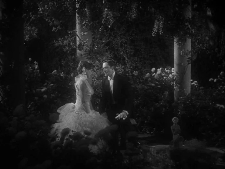 Dr. Jekyll and Mr. Hyde (1931) movie still: fullbody — A dark, dense garden at night features neoclassical columns and low-lying floral bushes. A…