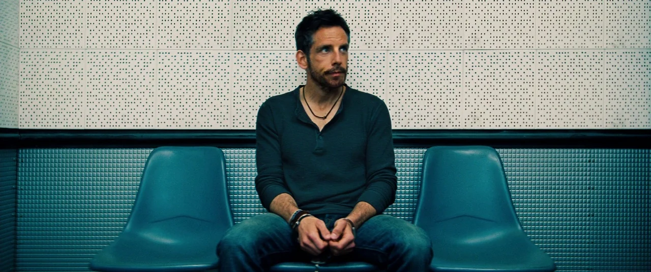 The Secret Life of Walter Mitty (2013) movie still: medium — A waiting area with perforated white acoustic panels above a dark teal metal wainscot.…