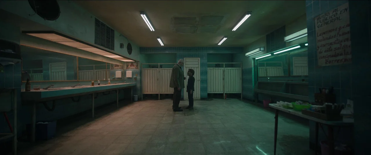Bardo: False Chronicle of a Handful of Truths (2022) movie still: wide — A spacious, tiled public restroom contains a long vanity mirror and…