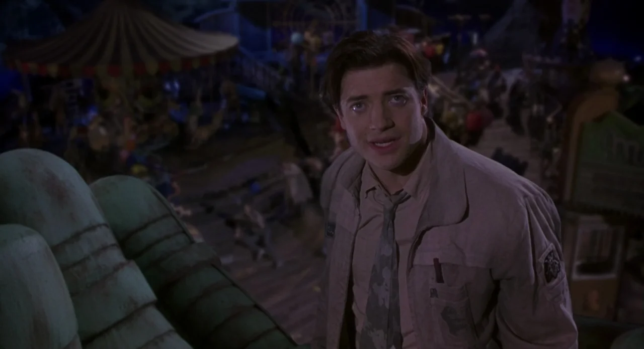 Monkeybone (2001) movie still: medium — A dark outdoor carnival area at night features a carousel in the background. A young man stands in the…