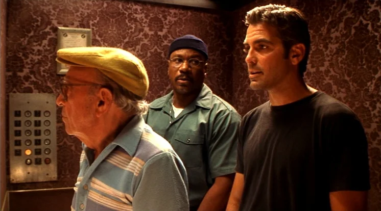Out Of Sight (1998) movie still: medium — An elevator interior features dark purple patterned wallpaper and a metal button panel. Three men stand…