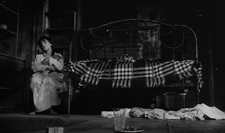 The Miracle Worker (1962) movie still: wide — A sparsely furnished room contains a dark metal bed frame and simple wooden shelves. A woman in a…