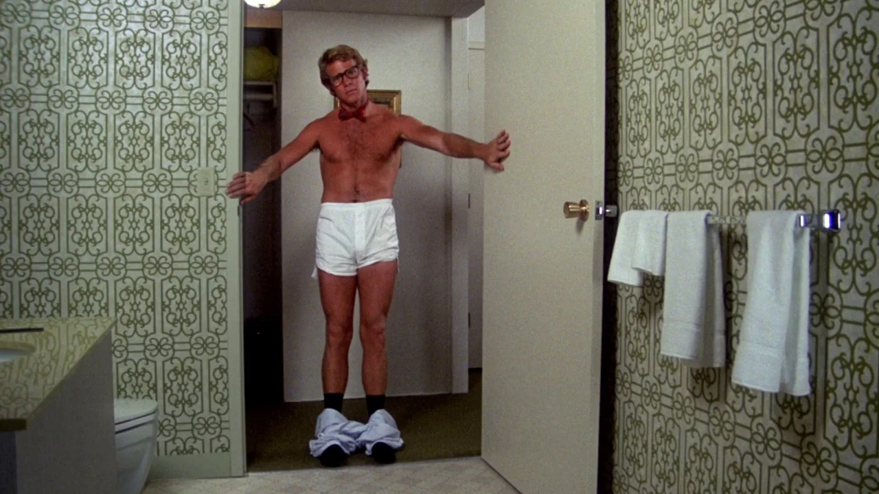 What’s Up, Doc? (1972) movie still: fullbody — A 1970s bathroom is decorated with prominent green and white geometric patterned wallpaper. A man…