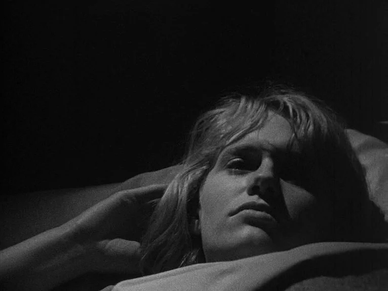 Cathy Come Home (1969) movie still: closeup — A dimly lit interior space with soft textures indicating a sleeping area. A person lies down resting…