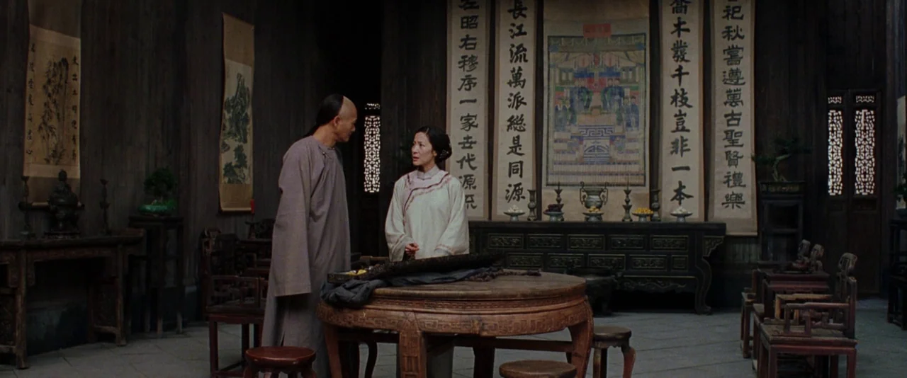 Crouching Tiger, Hidden Dragon (2000) movie still: fullbody — A dark, wood-paneled hall features traditional Chinese calligraphy scrolls and a…