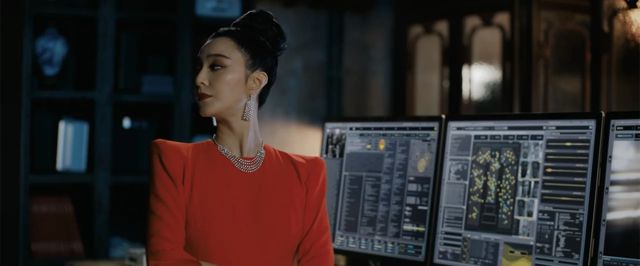 The 355 (2022) movie still: medium — A dark, modern room contains multiple computer monitors displaying data and digital information. A woman in a…