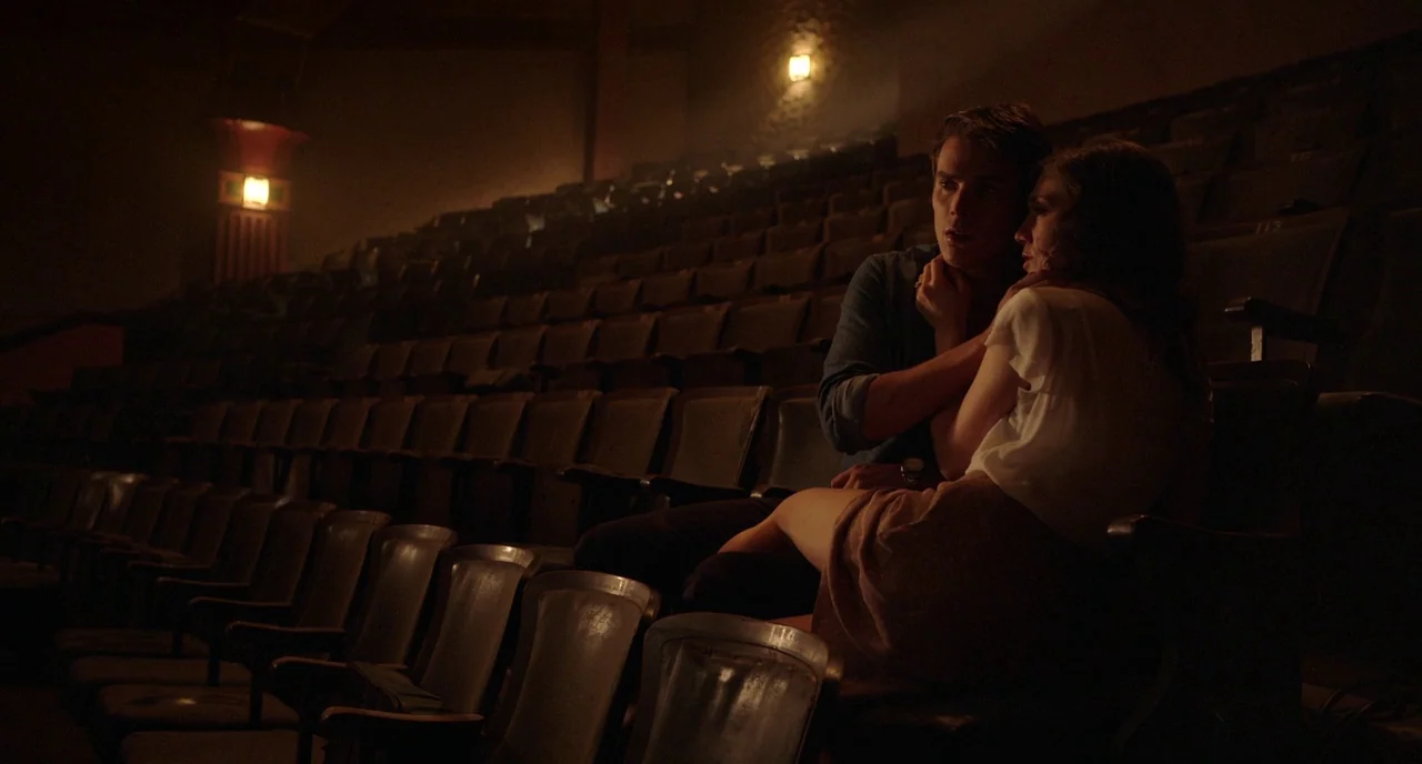 Nightmare Cinema movie still: wide — An empty, dimly lit auditorium featuring rows of aged velvet seats in descending tiers. A young man and woman…