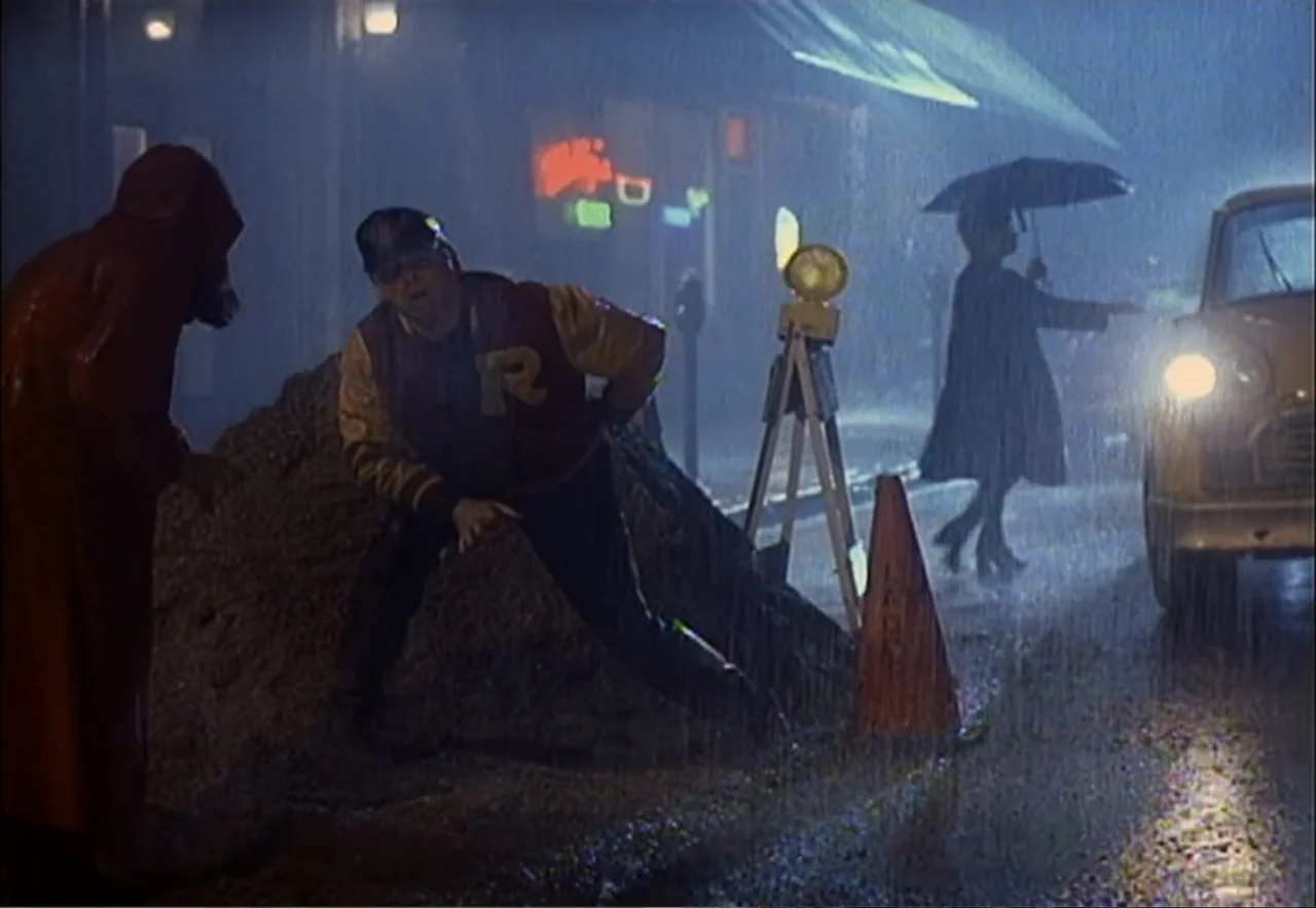 Chance of a Lifetime (1998) movie still: medium — A rain-drenched city street at night is illuminated by car headlights and neon signs. A man in a…
